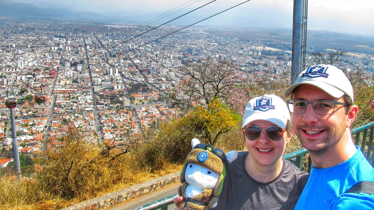 Vista do alto do Cerro San Bernardo, com o icônico bondinho do Teleférico San Bernardo de Salta em destaque, cercado pela paisagem da cidade de Salta e pela imponente Cordilheira dos Andes, na Argentina.