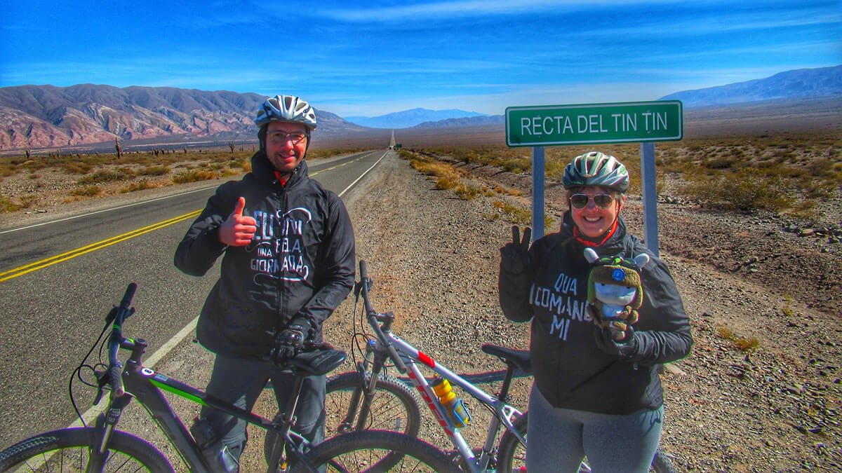 Imagem da Recta del Tin Tin, famosa estrada no Parque Nacional Los Cardones, na Cordilheira dos Andes, província de Salta, Argentina, durante um passeio de bicicleta. Vista panorâmica em um dia ensolarado, com céu azul e montanhas ao fundo.