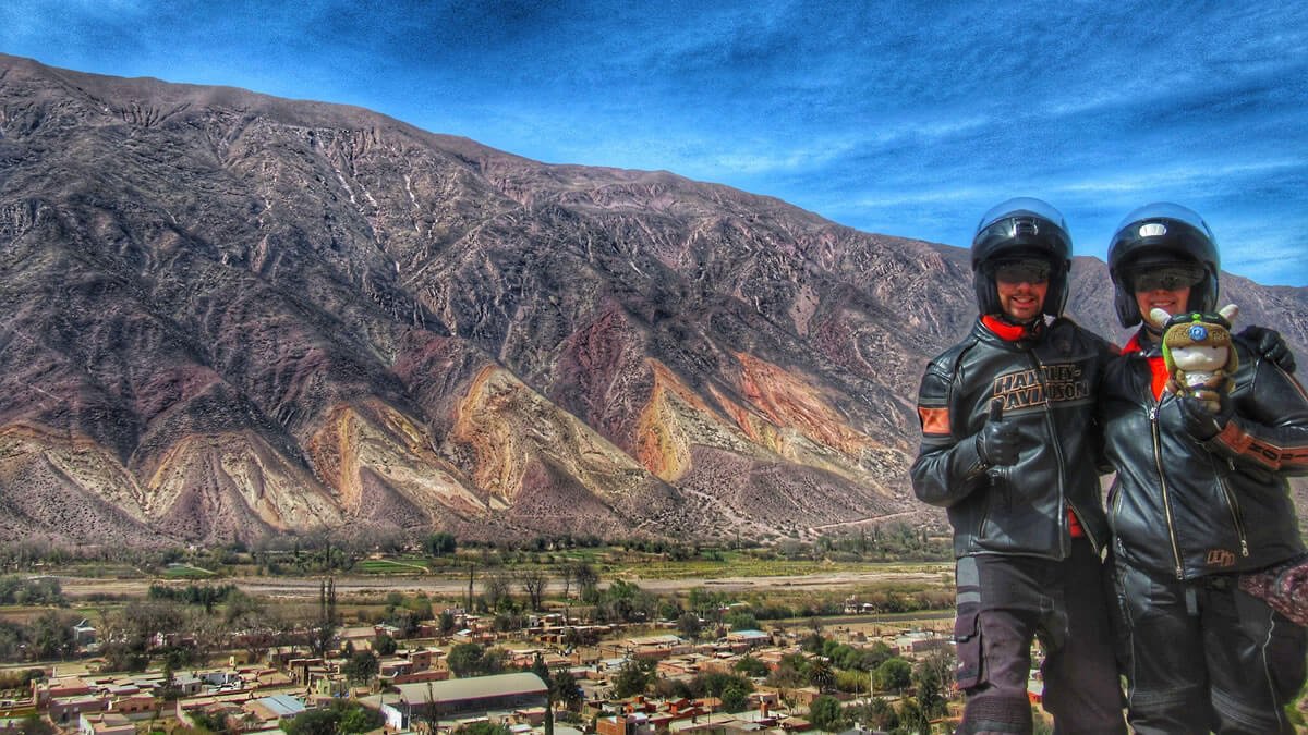 Vista do Mirador El Monolito, na Ruta Nacional 9, na Quebrada de Humahuaca, Argentina. Ao fundo, a deslumbrante montanha colorida Cerro La Paleta del Pintor, contrastando com o céu azul e a cidade pitoresca de Maimará, localizada às margens do Río Grande.