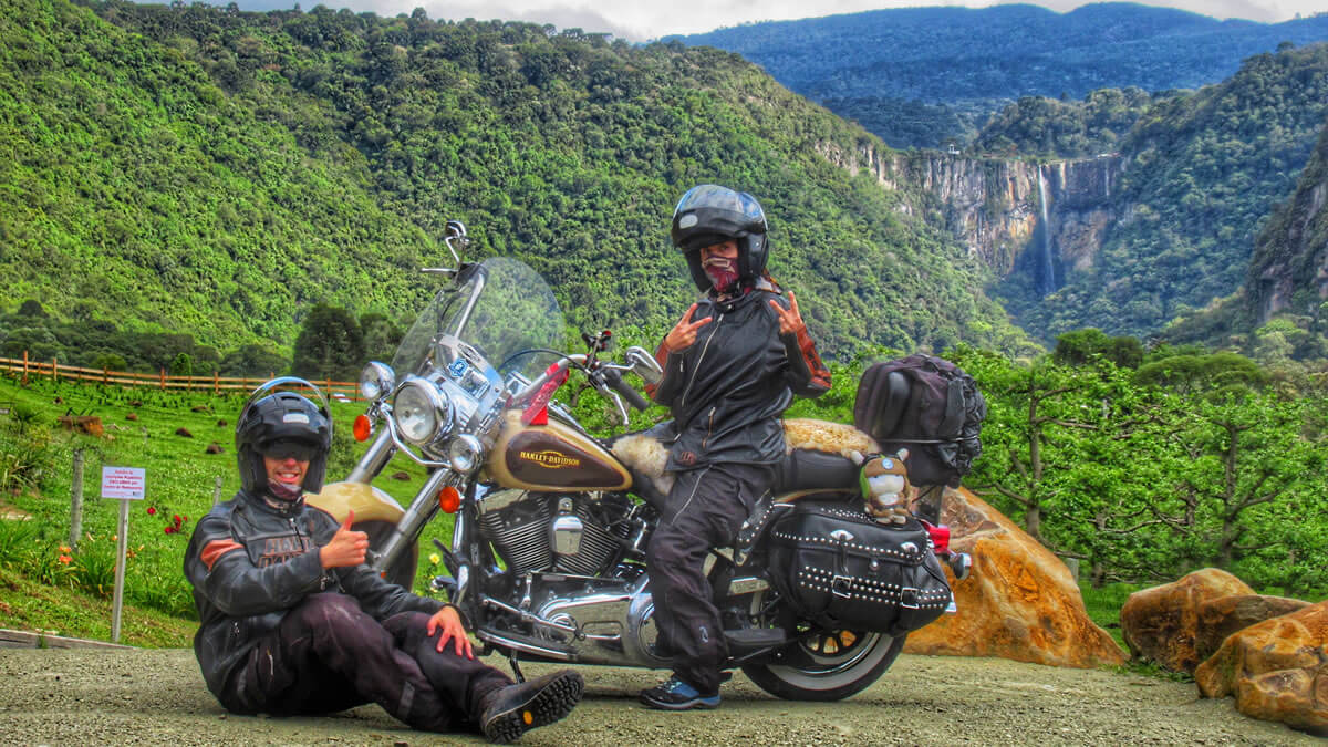 Foto espetacular de uma moto Harley-Davidson com a Cascata do Avencal ao fundo, destacando-se em meio à densa vegetação nativa de Urubici, Santa Catarina.