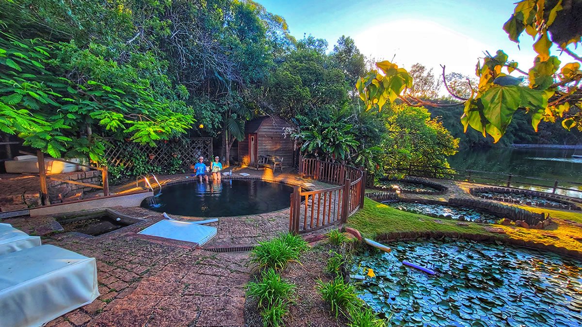 Área externa do Hotel Passarim em Capão Bonito, São Paulo, com piscina natural cercada pela Mata Atlântica, jardins exuberantes e lago, cenário ideal para observação de aves e contato com a natureza.
