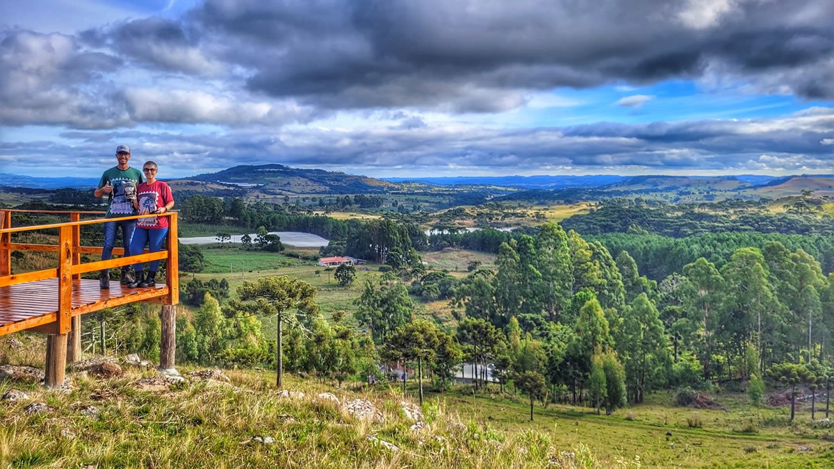 Casal em mirante com vista da paisagem rural em Urupema (SC), cenário da revoada dos papagaios-charão